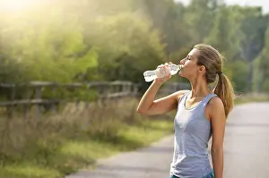 Young woman drink water while jogging outdoors