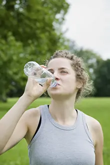 Young woman drinking from a bottle of mineral water after working out
