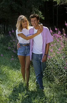 Young woman embraces young man walking in the forest