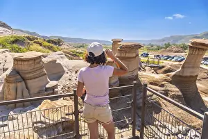 Young woman enjoying view of unique hoodoo rock formations at tourist attraction in drumheller