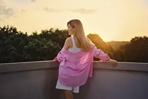 Young woman enjoys the beautiful sunset from her balcony