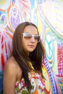 Young woman in glasses stand near graffiti wall