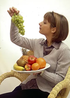 Young woman with grapes and fruit plate