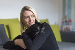 Young woman holding a black cat in her arms