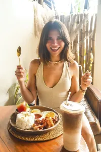 Young woman holding cutlery and smiling