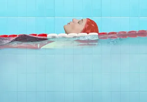 Young woman in an indoor swimming pool doing backstroke