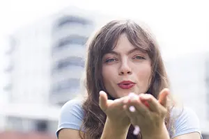 Young woman with long hair blowing into her hands