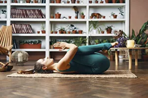 Young woman lying on the back with his knees doing twisting exercise at home