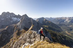 Young woman, mountaineer with climbing helmet looking at mountain landscape