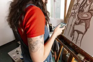 A young woman is painting a canvas in her home studio