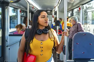 Young woman passenger holding a handrail inside a public bus