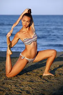 Young woman practicing yoga on the sea beach at sunset