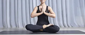 Young woman sits in a lotus position in a bright studio on a black mat. Yoga concept. Women's spiritual practices. Fitness