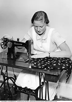 Framed Print : A young woman sits sewing at a Husqvarna sewing machine in the 1930s
