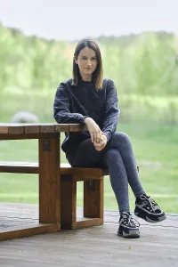 A young woman sits on a wooden bench beside a table