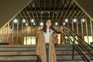 Young woman smiling while checking her smartphone