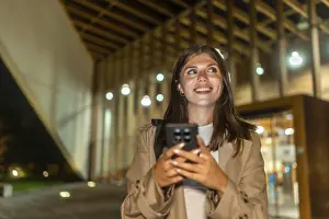Young woman smiling while holding a smartphone and looking up