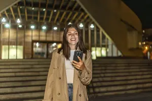 Young woman smiling while looking at her mobile phone outdoors