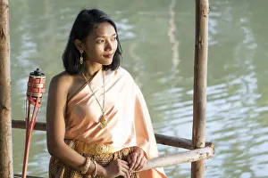 Young woman in traditional Thai clothes stands on the river bank
