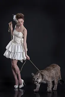 Young woman in a wedding dress holding puma on a leash