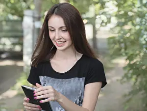 Young women smiling with taplet-pc in her hands outdoors