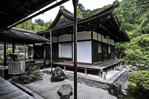 Zen garden with traditional pavilion surrounded by carefully arranged rocks and green vegetation
